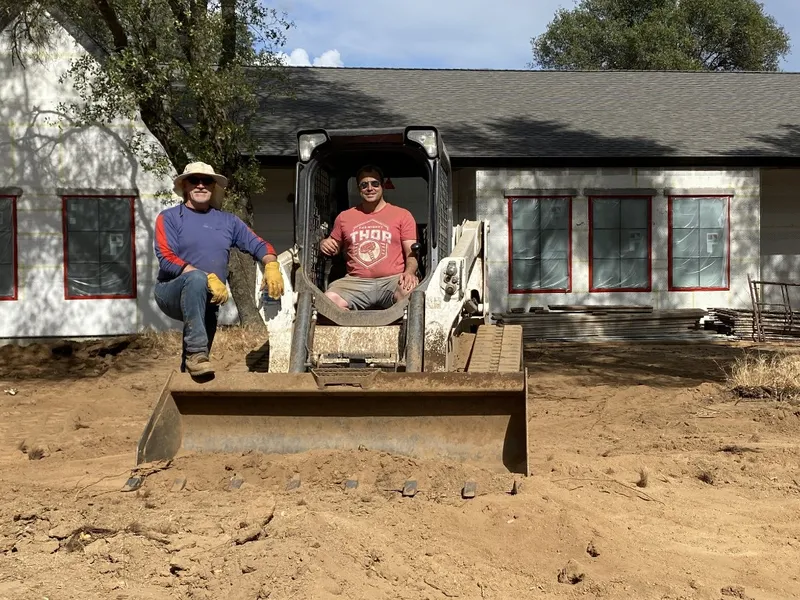 Marshall and his dad on a track loader at the house Marshall general-contracted